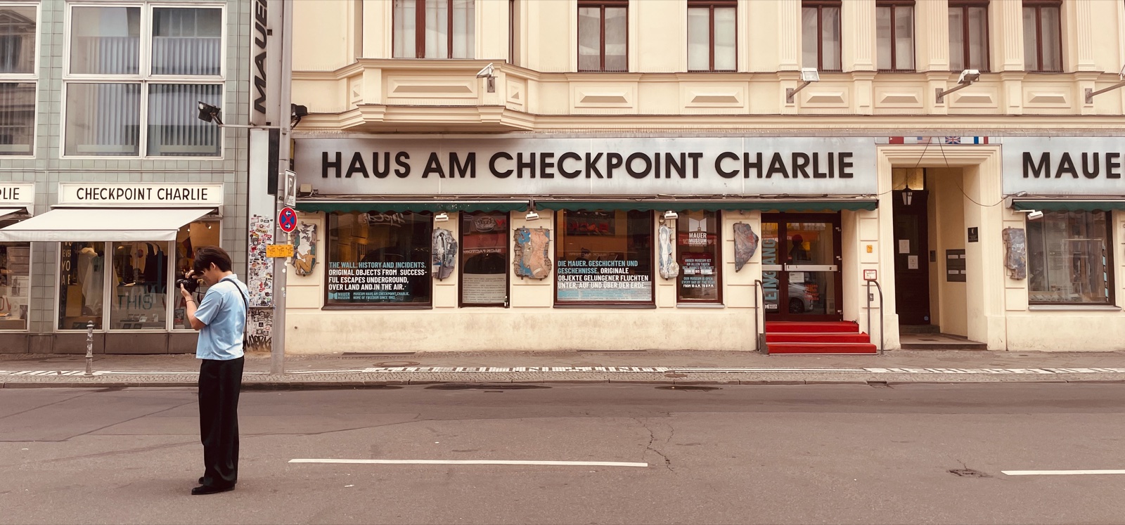 Person photographing Haus am Checkpoint Charlie from across the street in Berlin