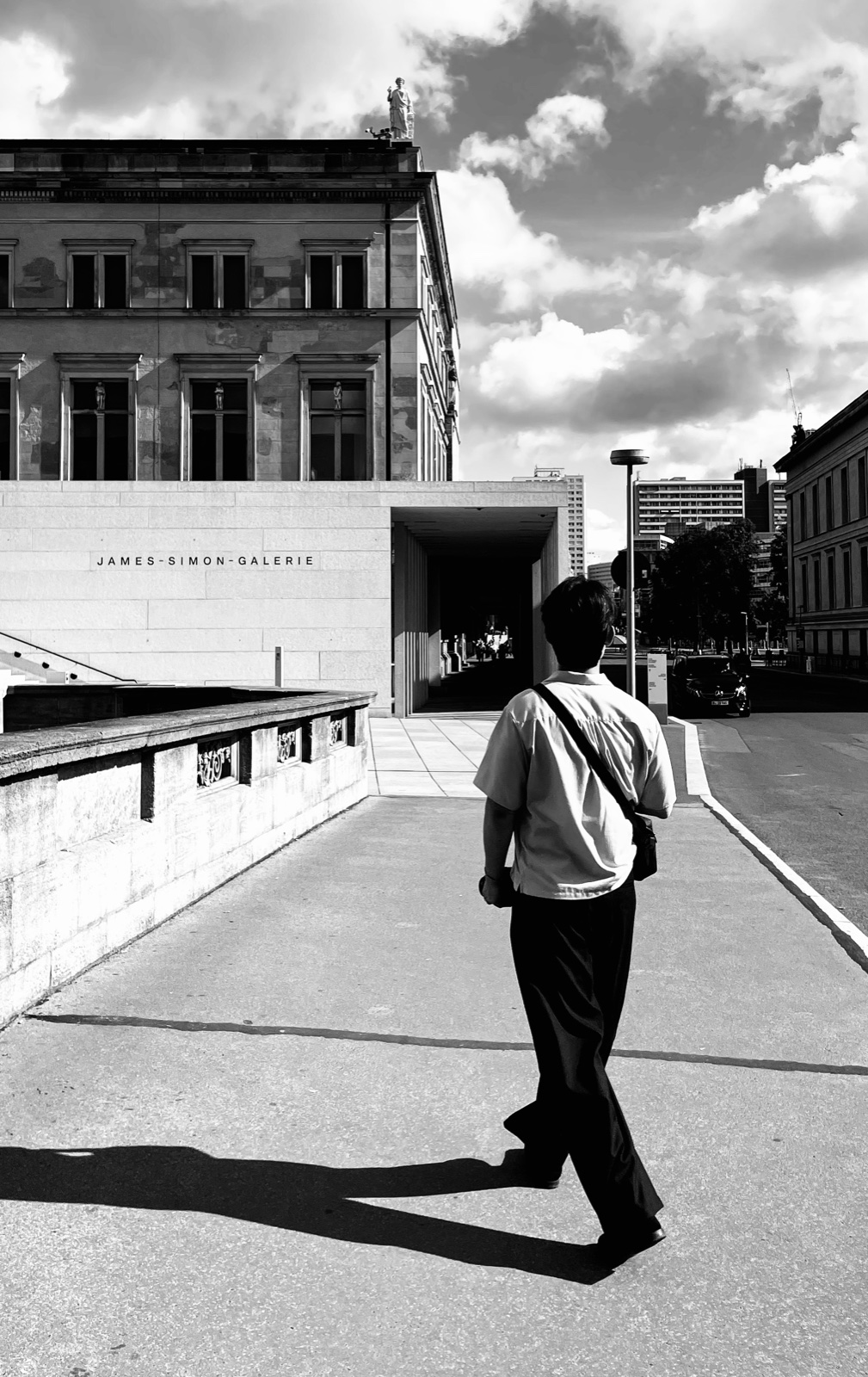Black-and-white shot of a person walking toward the James-Simon-Galerie in Berlin