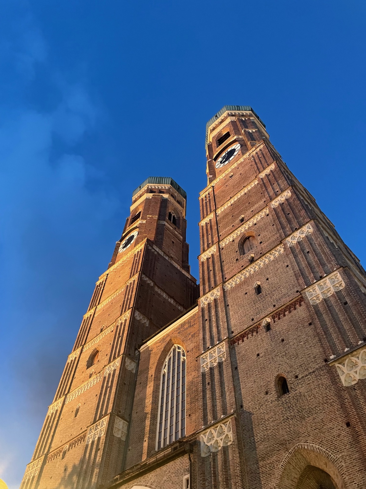 Looking up at the twin brick towers of Munich’s Frauenkirche against a blue sky